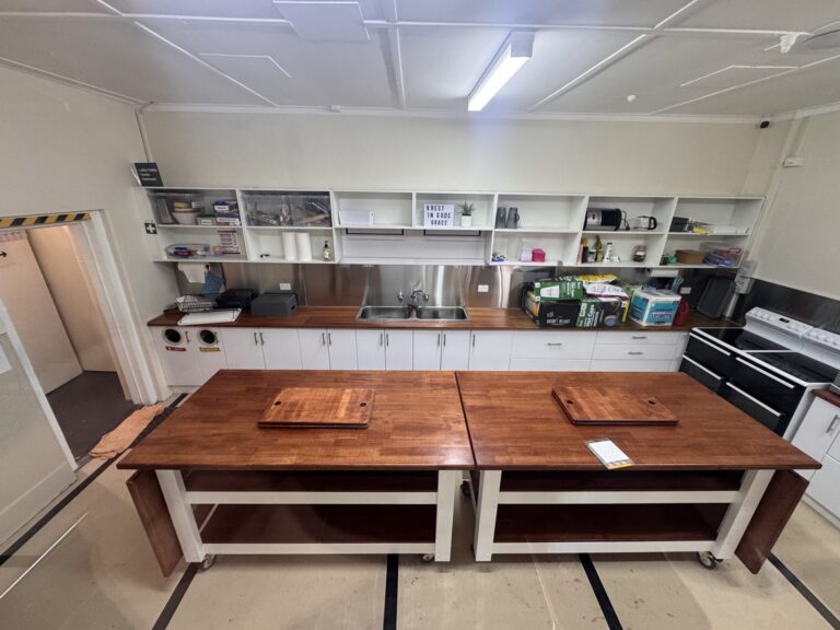Grace Chapel kitchen at Archies Creek, wide view of island benches, sink, shelving and fridge