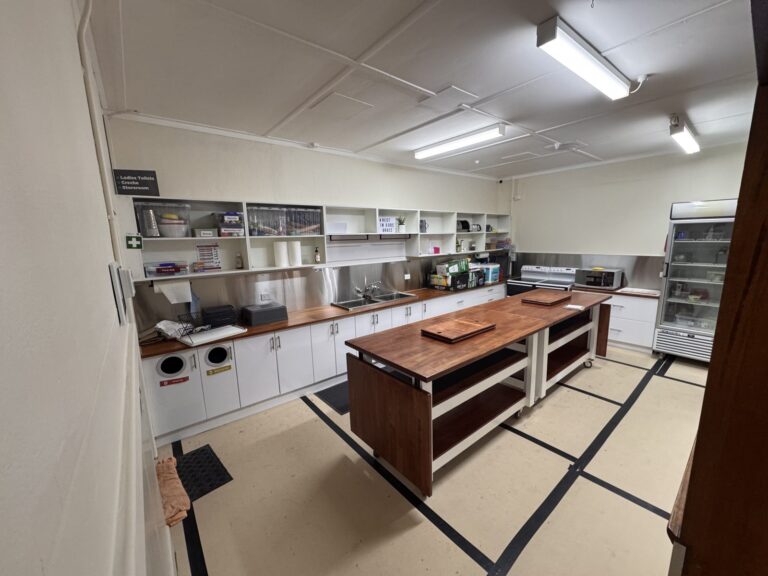 Grace Chapel kitchen at Archies Creek with two island benches on wheels, sink, open shelving and cooktops